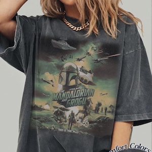 Pode incluir: Camiseta cinza escuro com um gr&aacute;fico de Star Wars apresentando The Mandalorian e Grogu, naves espaciais e personagens. O texto "THIS IS THE WAY" tamb&eacute;m &eacute; vis&iacute;vel. &Eacute; uma camiseta Comfort Colors Pepper.