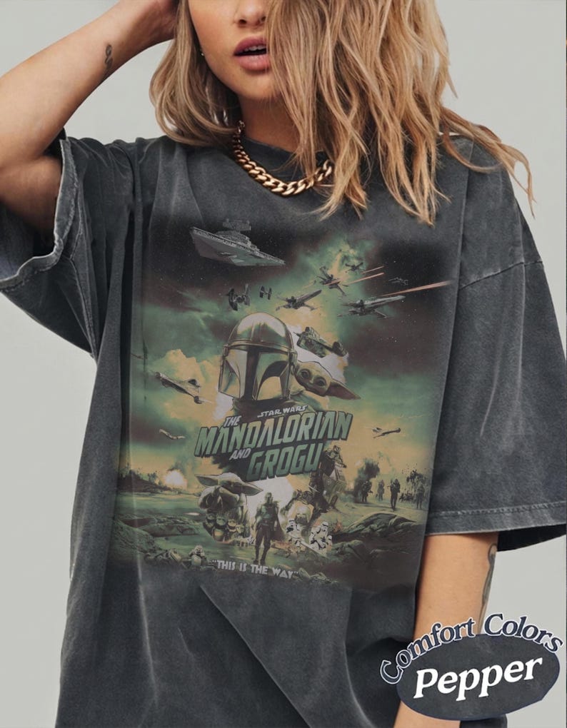 Pode incluir: Camiseta cinza escuro com um gr&aacute;fico de Star Wars apresentando The Mandalorian e Grogu, naves espaciais e personagens. O texto "THIS IS THE WAY" tamb&eacute;m &eacute; vis&iacute;vel. &Eacute; uma camiseta Comfort Colors Pepper.
