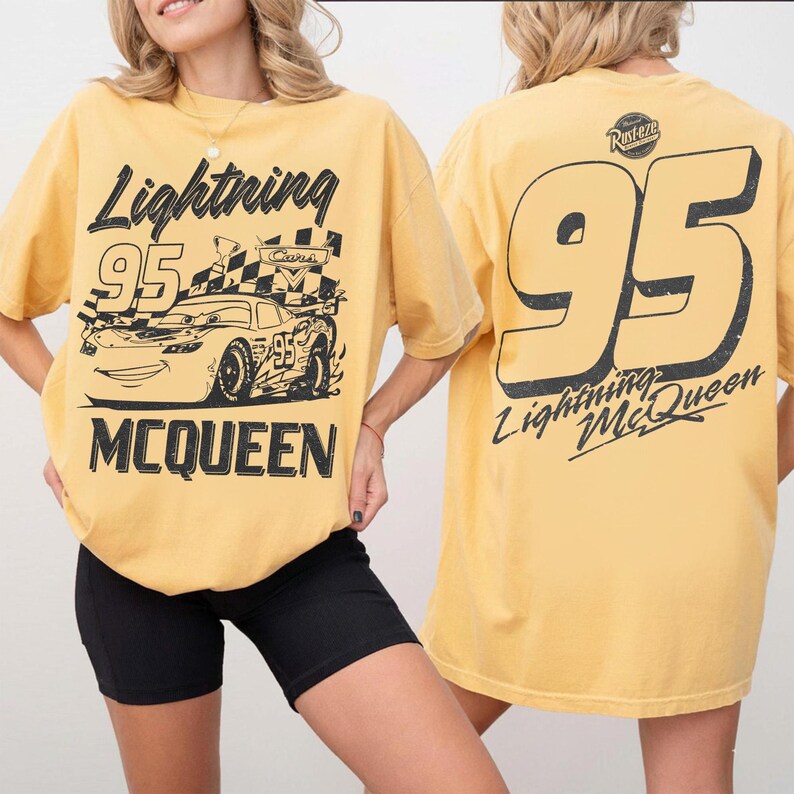 May include: Mustard yellow t-shirt featuring a graphic of Lightning McQueen from the Cars movie. The front of the shirt displays the text "Lightning McQueen" and "95" with a race car design. The back of the shirt has a large "95" and "Lightning McQueen" text.