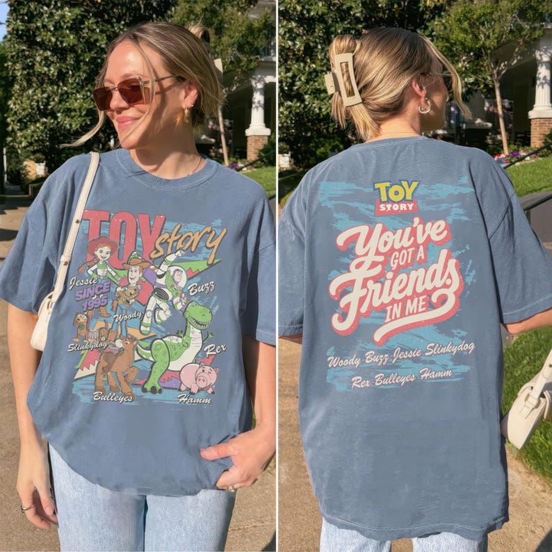 K&ouml;nnte beinhalten: Ein blaues kurz&auml;rmeliges T-Shirt mit Toy Story-Grafiken. Die Vorderseite zeigt Jessie, Woody, Buzz, Slinky Dog, Bullseye und Hamm mit dem Text Toy Story und Since 1995. Die R&uuml;ckseite zeigt den Text You've Got A Friend In Me.