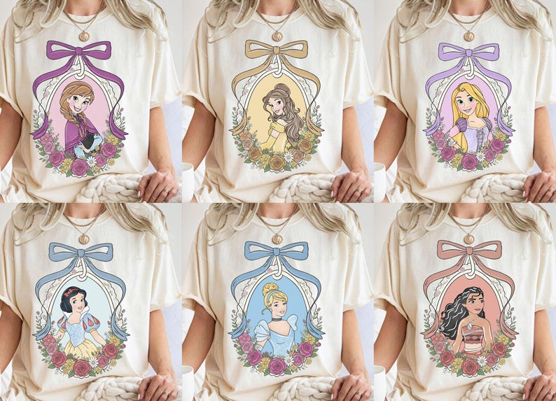 K&ouml;nnte beinhalten: Cremefarbene T-Shirts mit sechs verschiedenen Prinzessinnen-Designs. Jedes Design ist von einem dekorativen Oval mit Schleife und floralen Akzenten umrahmt. Die Prinzessinnen sind Anna, Belle, Rapunzel, Schneewittchen, Aschenputtel und Moana.