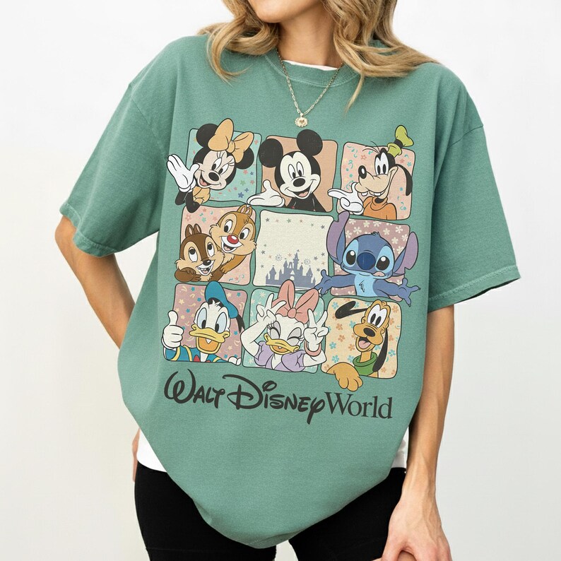K&ouml;nnte beinhalten: Gr&uuml;nes T-Shirt mit einem Rasterdesign, das Disney-Charaktere wie Micky Maus, Minnie Maus und Donald Duck zeigt. Die Worte "Walt Disney World" sind in einer Schriftart am unteren Rand des Shirts aufgedruckt.