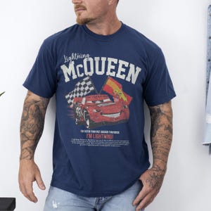 May include: Navy blue t-shirt featuring Lightning McQueen from the Cars movie. The graphic includes the text "Lightning McQueen" above a red race car with checkered and yellow flags. The text "I'M LIGHTNING!" is also visible.