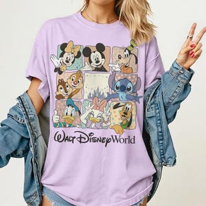 K&ouml;nnte beinhalten: Ein helllila T-Shirt mit einem Raster von Disney-Figuren, darunter Micky Maus, Minnie Maus, Goofy, Donald Duck, Daisy Duck, Chip und Chap, Stitch und Pluto. Die Worte "Walt Disney World" sind unten in schwarzer Schrift gedruckt.