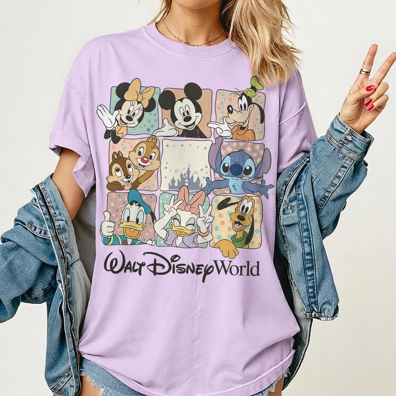 K&ouml;nnte beinhalten: Ein helllila T-Shirt mit einem Raster von Disney-Figuren, darunter Micky Maus, Minnie Maus, Goofy, Donald Duck, Daisy Duck, Chip und Chap, Stitch und Pluto. Die Worte "Walt Disney World" sind unten in schwarzer Schrift gedruckt.
