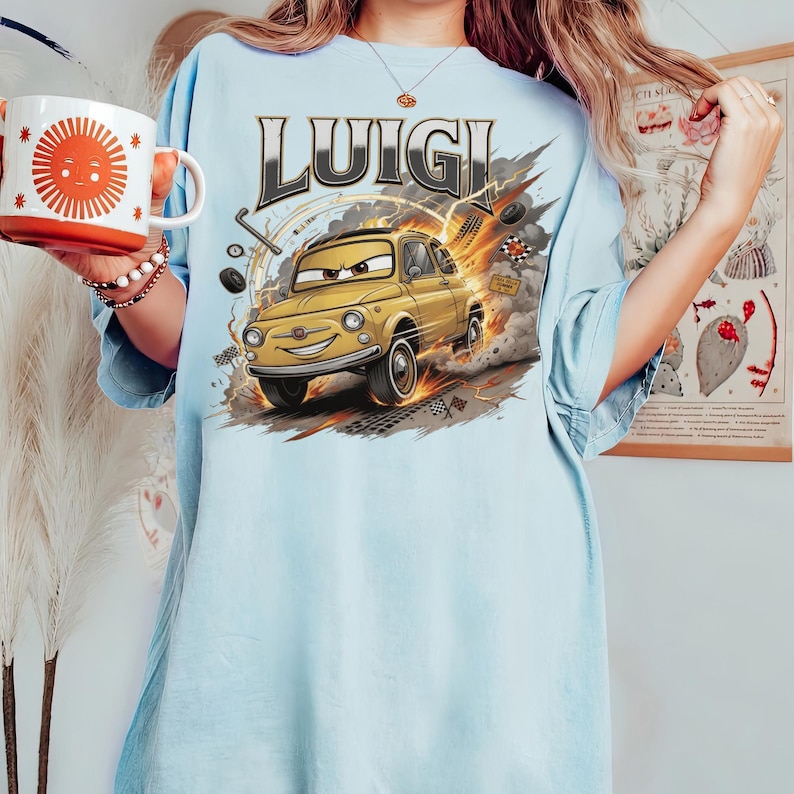 以下が含まれることがあります： 「LUIGI」の文字と、黄色の車の漫画イラストが描かれた水色のTシャツ。車はスピードラインと煙のエフェクトで動きが表現されています。
