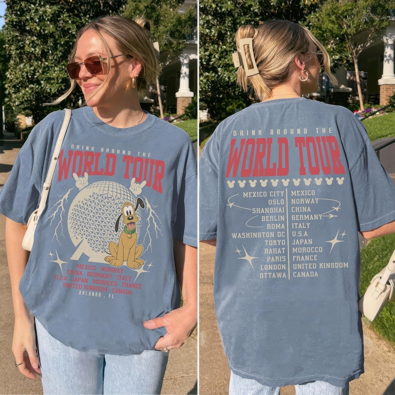 May include: A blue t-shirt with the text "DRINK AROUND THE WORLD TOUR" in red. The front features a graphic of a globe, lightning bolts, and Pluto. The back lists cities like Mexico City, Oslo, and Tokyo.