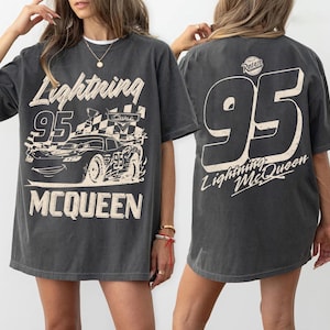 May include: A white ceramic mug with a black handle and the text "But First, Coffee" in a black, handwritten-style font. The mug is on a white surface.