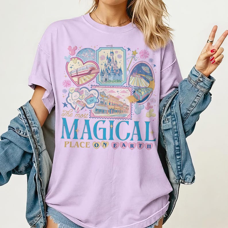 May include: A light purple t-shirt with the text "The most MAGICAL PLACE ON EARTH" in blue and pink. The shirt features colorful illustrations of a train, a castle, and other theme park imagery.