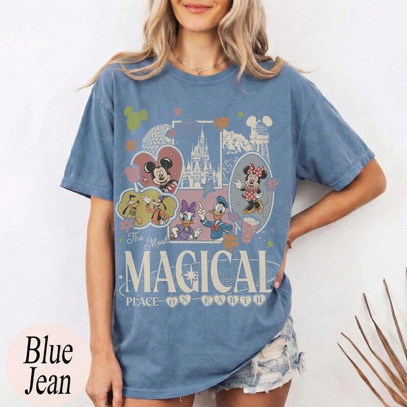 May include: Blue jean t-shirt featuring a colorful graphic with Mickey and Minnie Mouse, Donald and Daisy Duck, and other Disney characters. The shirt has the text "The Most Magical Place on Earth."