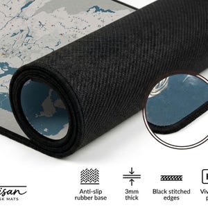 Puede incluir: Alfombrilla de escritorio enrollada con un dise&ntilde;o de mapa del mundo en tonos grises y azules. La alfombrilla tiene una base de goma antideslizante negra, bordes cosidos negros y tiene 3 mm de grosor. El texto "Artisan DESK MATS" es visible.