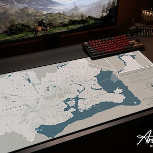Puede incluir: Una alfombrilla de escritorio grande con un dise&ntilde;o de mapa detallado en tonos azules y grises. El mapa incluye caracter&iacute;sticas geogr&aacute;ficas y texto, con las palabras "PYWEL CONTINENT" y "Artisan DESK MATS" visibles. Un teclado y un rat&oacute;n tambi&eacute;n est&aacute;n en el escritorio.