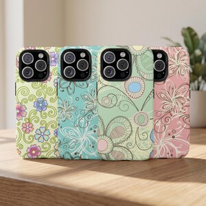 May include: Four smartphone cases arranged in a row, each featuring a distinct floral and swirl pattern. The cases display color palettes of light green, turquoise, mint green, and soft pink, with intricate line art and circular flower motifs.