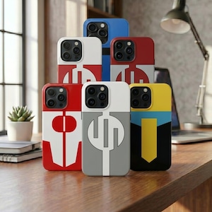 May include: A stack of colorful phone cases with geometric designs. The cases feature a variety of colors, including red, white, blue, gray, and yellow. Each case has a unique graphic design, with a camera cutout on the top.