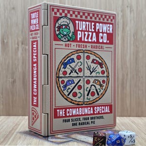 May include: A rectangular beige storage box featuring a Turtle Power Pizza Co. graphic with a cartoon turtle chef, a pizza divided into four sections with ninja weapons, and the text The Cowabunga Special, Four Slices, Four Brothers, One Radical Pie.