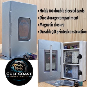 May include: A silver 3D-printed card case with a magnetic closure, designed to hold 100 double-sleeved cards. It features a dice storage compartment and a window to display a card. The Gulf Coast Game Vault logo is visible.