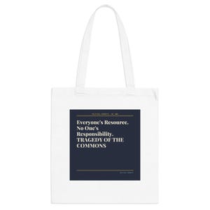 Puede incluir: Bolso tote blanco con un rectángulo azul marino con el texto "Everyone's Resource. No One's Responsibility. TRAGEDY OF THE COMMONS" en letras blancas y doradas. El bolso tiene dos asas blancas.