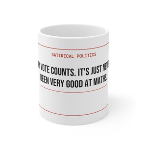 Może przedstawiać: Biały ceramiczny kubek z czarnym napisem "My vote counts. It's just never been very good at maths". Nad tekstem czerwonymi literami napisano "Satirical Politics". Kubek ma czerwone linie u góry i u dołu.