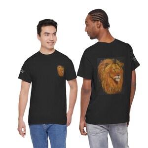 Op de afbeelding: Zwarte t-shirts met een leeuwenafbeelding. Eén shirt heeft een kleine leeuwenafbeelding op de linkerborst. Het andere shirt heeft een grotere leeuwenafbeelding op de rug. De leeuwenafbeeldingen zijn in tinten oranje, bruin en geel.