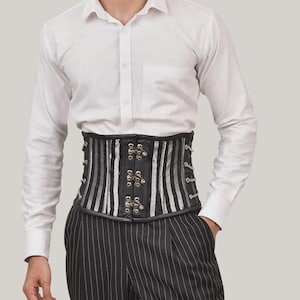 May include: A white long-sleeved button-down shirt worn with a black and silver striped corset featuring a front metal clasp closure and side lacing details, paired with black pinstriped trousers. The corset has a structured, waist-cinching design.