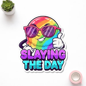 May include: A colorful sticker featuring a cartoon ice cream scoop wearing pink sunglasses and giving a thumbs up. The text "SLAYING THE DAY" is written in purple and blue. The ice cream is rainbow-colored.