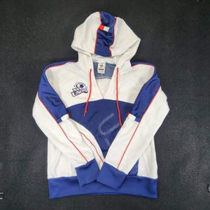 May include: White and blue hooded sweatshirt with the text "NEW UNITED". The sweatshirt has a blue mesh panel on the front and sleeves, with red accents. The hood is white with a blue and red stripe.