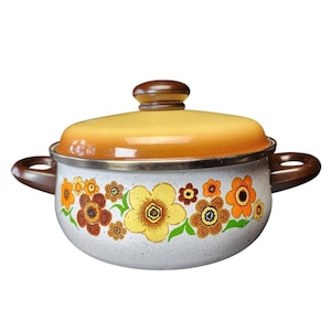 May include: A round, white enameled metal pot with a speckled finish and two brown side handles. It features a vibrant floral pattern in shades of yellow, orange, and brown. The matching lid has a yellow-to-orange gradient and a brown knob.
