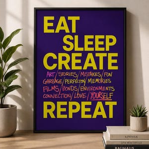 May include: A framed rectangular wall art print with a dark purple background. The text EAT, SLEEP, CREATE, and REPEAT is printed in large yellow capital letters. Between these, smaller handwritten-style text includes ART, STORIES, MISTAKES, FUN, GARBAGE, PERFECTON, MEMORIES, FILMS, BONDS, ENVIRONMENTS, CONNECTION, LOVE, and YOURSELF.