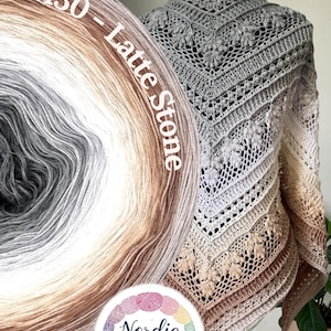 Puede incluir: Un chal triangular de ganchillo con un intrincado patrón de hojas y un degradado de color que va del gris oscuro al blanco y al marrón claro. El texto M30 - Latte Stone es visible, junto a un logotipo circular que dice Nordic Twist.