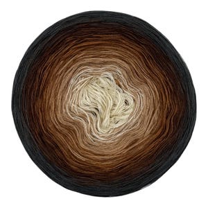 Puede incluir: Un ovillo de hilo circular con un degradado de color. El centro es de color crema claro, que cambia gradualmente a través de varios tonos de marrón y beige, llegando finalmente a un color negro sólido en el borde exterior del círculo.