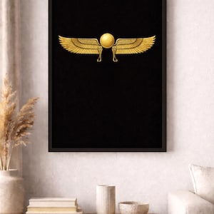 May include: Framed artwork with a gold winged sun disc on a black background. The print is displayed on a wall above a wooden cabinet. The cabinet has decorative items on top.