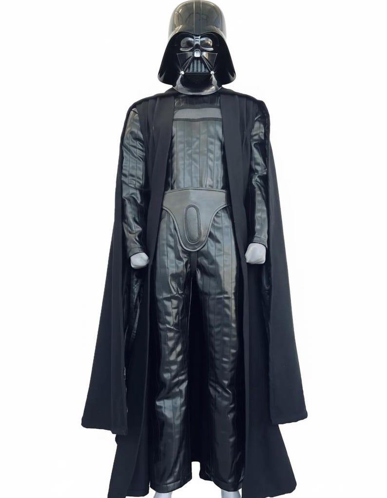 Full-body shot of a high-quality handmade Darth Vader cosplay costume with a long black flowing cape, quilted flight suit jumpsuit, inner tunic, and soft parts, displayed on a model against a clean, solid white background.