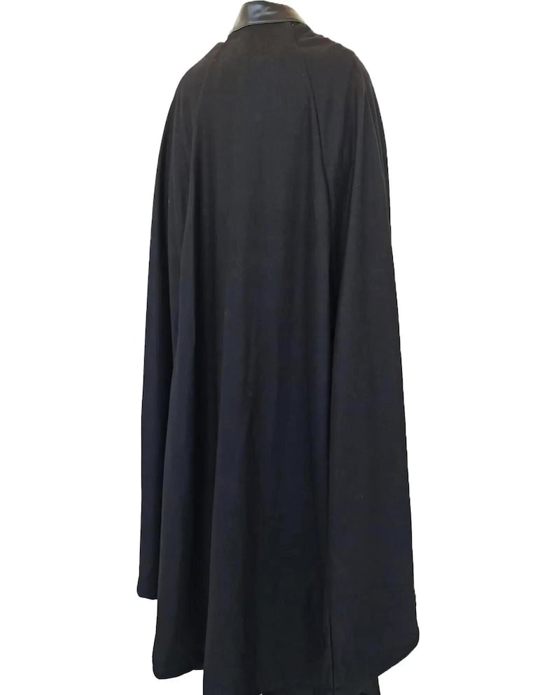 Full-body shot of a high-quality handmade Darth Vader cosplay costume with a long black flowing cape, quilted flight suit jumpsuit, inner tunic, and soft parts, displayed on a model against a clean, solid white background.