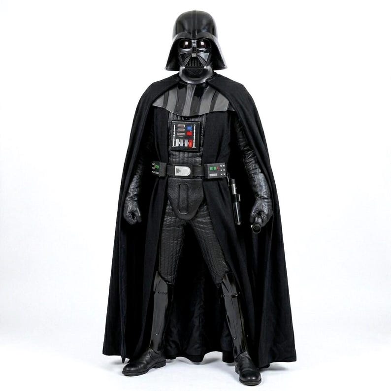 Full-body shot of a high-quality handmade Darth Vader cosplay costume with a long black flowing cape, quilted flight suit jumpsuit, inner tunic, and soft parts, displayed on a model against a clean, solid white background.