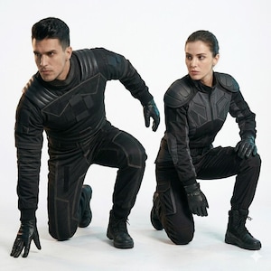 May include: Two individuals wearing black tactical uniforms consisting of long-sleeved jackets with padded shoulders and matching trousers. The outfits feature reinforced stitching, utility pockets, and black leather gloves. Both wear black combat boots.