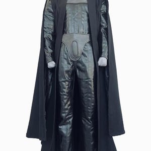 Full-body shot of a high-quality handmade Darth Vader cosplay costume with a long black flowing cape, quilted flight suit jumpsuit, inner tunic, and soft parts, displayed on a model against a clean, solid white background.