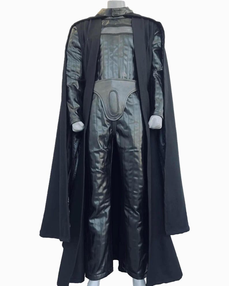 Full-body shot of a high-quality handmade Darth Vader cosplay costume with a long black flowing cape, quilted flight suit jumpsuit, inner tunic, and soft parts, displayed on a model against a clean, solid white background.