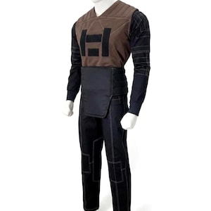 A premium galactic bounty hunter cosplay costume worn by a male model looking sideways, showcasing the screen-accurate ribbed double-sleeve detailing, dark brown flak vest, and black tailored undersuit over a solid white background.