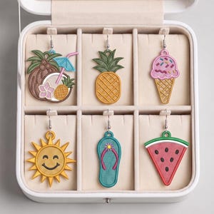 May include: A collection of six embroidered earrings in a white jewelry box. The earrings feature summer-themed designs: a coconut with a cocktail, a pineapple, an ice cream cone, a smiling sun, a flip-flop, and a watermelon slice.