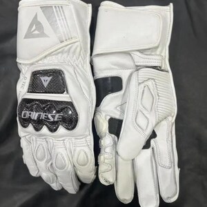 Puede incluir: Par de guantes blancos de moto con detalles en negro. Los guantes muestran un logotipo y el nombre de la marca "Dainese". Tienen refuerzos en los nudillos y un cierre de mu&ntilde;eca seguro.
