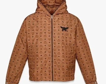 Chaqueta cortavientos con capucha y monograma Visetos de MCM en marrón coñac con cremallera con logotipo, estilo de diseñador.