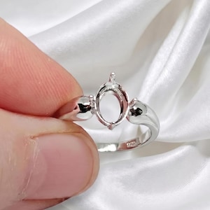 May include: A silver-colored ring setting featuring an oval-shaped prong mount designed to hold a gemstone. The band is smooth and polished, with the number 925 clearly stamped on the inner surface, indicating sterling silver composition.