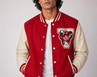 May include: Red varsity jacket with cream-colored sleeves, white stripes, and a patch featuring a football-themed design. The jacket has a button-up front and a classic athletic style.