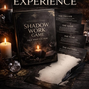 Op de afbeelding: Een donkere afbeelding met een boek getiteld "SHADOW WORK GAME" met de tekst "FACE WHAT YOU HIDE". Kaarten en een veer zijn zichtbaar. Aangestoken kaarsen en de tekst "THIS IS NOT A JOURNAL... IT'S A SHADOW EXPERIENCE" creëren een mysterieuze sfeer.