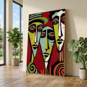 Könnte beinhalten: Abstrakter Kunstdruck mit drei stilisierten Gesichtern mit länglichen Merkmalen und kräftigen Farben. Das Kunstwerk verwendet eine Palette aus Rot, Grün, Gelb und Schwarz mit strukturiertem Aussehen. Das gerahmte Stück wird in einem hellen Raum ausgestellt.