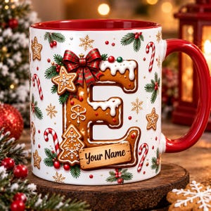 May include: A white ceramic mug with a red interior and handle, featuring a large gingerbread letter E decorated with white icing, a plaid bow, and a wooden sign reading Your Name, surrounded by gingerbread cookies and candy canes.