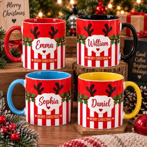 May include: Four ceramic mugs with red and white vertical stripes, featuring a green holly garland, black reindeer antlers, and a central white label with the names Emma, William, Sophia, or Daniel and the text Merry Christmas in red.
