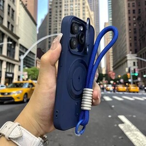 Könnte beinhalten: Marineblaue Handyhülle mit Kameraabdeckung und blauem Umhängeband. Das Gehäuse hat ein kreisförmiges Design mit einem Blitzsymbol. Das Umhängeband ist blau mit einem weißen und grauen Akzent.