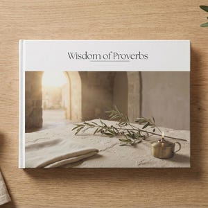 May include: A book titled "Wisdom of Proverbs" with a photograph of an ancient setting. A small brass oil lamp, olive branch, and a beige vase with a sprig of greenery are also present. The items are arranged on a wooden surface.