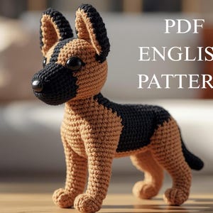 May include: A crocheted German Shepherd dog in tan and black. The dog has large black eyes and a black nose. The text "PDF ENGLISH PATTERN" is displayed in white letters.